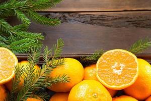 Fresh tangerines in brown box on wooden background with green fir branches. Frame, copy space, holiday and winter fragrance, new year, Christmas. Healthy food, orange juice, shop window. Slice and cut photo