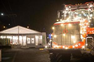 Kaluga, Russia, December 18, 2020. Decorated with bright lights garland a big truck on the city street. Christmas market, new year's eve. Exhibition of farm, tractor Kirovets. Copy space photo