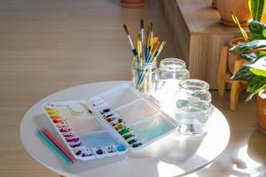 la paleta de colores, el pincel y la botella de agua se colocaron en la sala del estudio de arte. foto