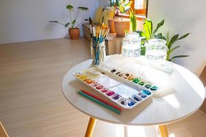 la paleta de colores, el pincel y la botella de agua se colocaron en la sala del estudio de arte. foto