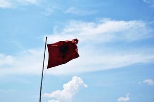 waving the flag of Albania against the blue sky photo