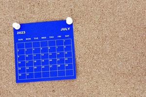 calendario azul de julio de 2023 con pin en la cartelera del boletín de corcho. foto