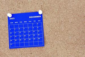 December 2023 blue calendar with pin on cork bulletin billboard. photo