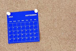 September 2023 blue calendar with pin on cork bulletin billboard. photo