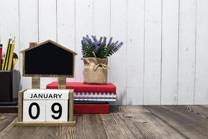 January 09 calendar date text on white wooden block with stationeries on wooden desk photo