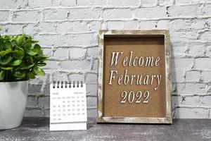 Welcome february 2022 text on wooden frame and February 2022 calendar. photo