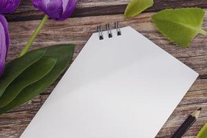 Notepad and pencil with flowers on wooden desk. Copy space. photo