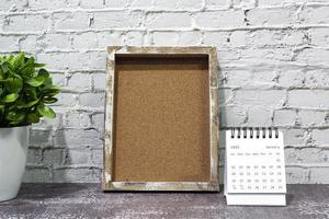 January 2022 white calendar with wooden frame and potted plant on wooden desk. photo