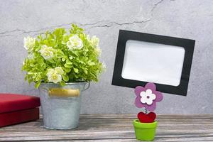 Paper frame with potted plant on wooden background. Copy space. photo