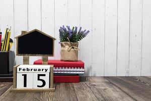 14 de febrero texto de fecha de calendario en bloque de madera con papelería en escritorio de madera. foto