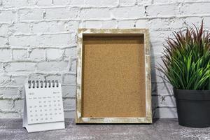 March 2022 white calendar with wooden frame and potted plant on wooden desk. photo