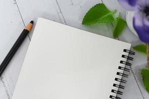 Notepad and pencil with flowers on wooden desk. Copy space. photo