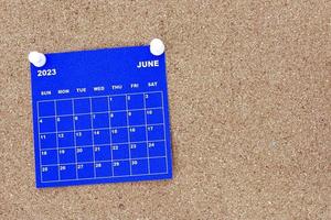 June 2023 blue calendar with pin on cork bulletin billboard. photo