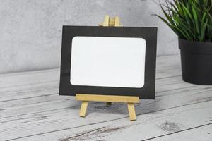 Paper frame with potted plant and flowers on wooden background. photo