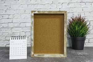 April 2022 white calendar with wooden frame and potted plant on wooden desk. photo