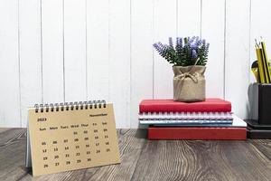 Brown November 2023 calendar on wooden desk with office stationery. photo