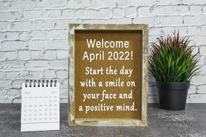 Motivational and inspirational quote on wooden frame with April 2022 calendar. photo