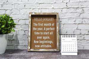 Inspirational and motivational quote on wooden frame and January 2022 calendar. photo