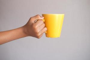 close up of man hand holding yellow color mug photo