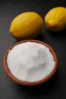 Coarse salt in a bowl and lemon on black background photo