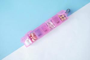 top view of medical pills in a pink color pill box on table photo