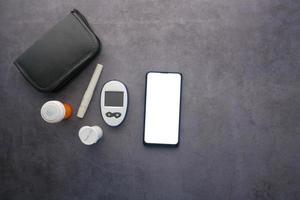 Teléfono inteligente y herramientas de medición para diabéticos y píldoras en la mesa foto
