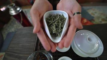 Woman hold small ceramic container of loose leaf green tea during tea ceremony video