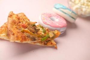 rebanada de pizza de queso en un plato, donuts y palomitas de maíz en rosa foto