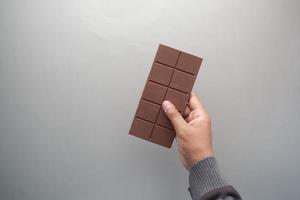 top view of men golding a dark chocolate on gray background photo