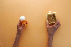 top view of senior women holding medical pill container and pill box photo