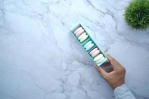 macaroon in a paper box on light green background photo