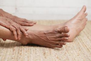 Close up on senior women feet and hand massage on injury spot. photo