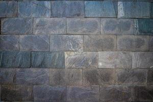 Grey stone wall with different sized stones, modern siding close up. Texture of a stone wall. Old castle stone wall texture background. Stone wall as a background or texture. Design element. photo