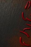 spices concept The spicy long thin red chilis placed with its powder sprinkling on the black background
