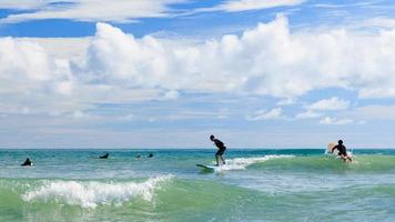 A young boy wearing swimming goggles stands on a soft board while practicing surfing in a beginner's class. photo