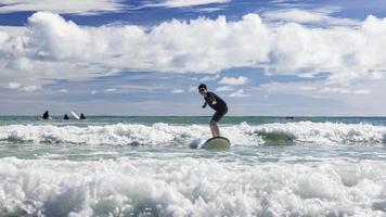 A young boy wearing swimming goggles stands on a soft board while practicing surfing in a beginner's class. photo