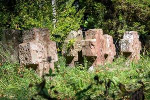 Very old tombstones made of red sandstone overgrown with grass and weeds photo