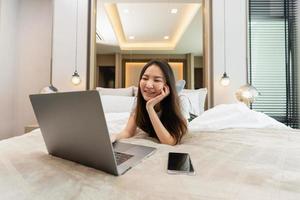 concepto de dormitorio en la cómoda cama una adolescente acostada con sus dispositivos electrónicos, la computadora portátil y el teléfono inteligente