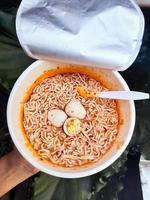 Taza picante de fideos instantáneos con aderezos adicionales de huevos de codorniz cocidos, muy deliciosos y sabrosos. foto