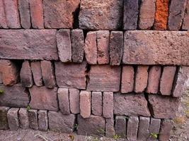 Portrait of a pile of bricks that have long been exposed to the sun and rain overgrown with small plants and moss, it is a building material made of burnt clay. photo