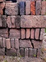 Portrait of a pile of bricks that have long been exposed to the sun and rain overgrown with small plants and moss, it is a building material made of burnt clay. photo