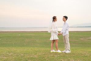 Happy young Asian couple in bride and groom clothing photo