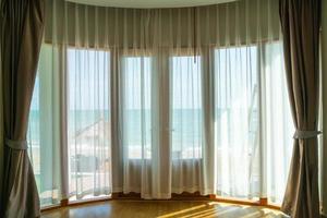 curtain and glass window with sea beach view outside photo