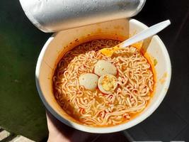 Taza picante de fideos instantáneos con aderezos adicionales de huevos de codorniz cocidos, muy deliciosos y sabrosos. foto