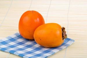 Persimmon on wooden background photo