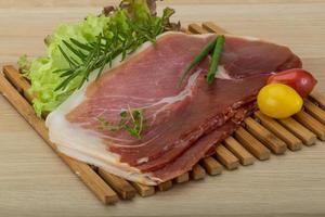 Prosciutto on wooden board and wooden background photo