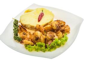 Garlic shrimps with potato on the plate and white background photo