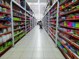 Jombang, East Java, Indonesia, 2022 -  a quiet shop aisle with rows of shelves filled with colorful household items or utensils retail, photo