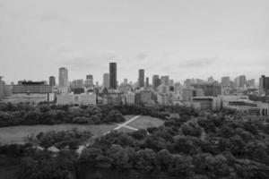 View of Osaka's skyline from east of downtown in black and white. Public park in the foreground. Tall buildings include office buildings and residential high-rises. photo