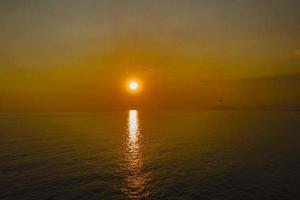 Calm sea with sunset sky and sun over clouds. Meditation ocean and sky background. photo